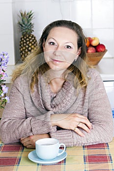 Portrait of happy woman with coffee in kitchen