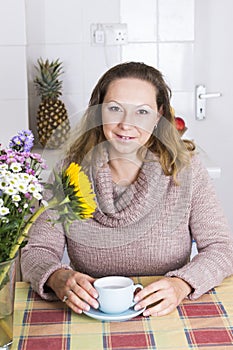 Portrait of happy woman with coffee in kitchen