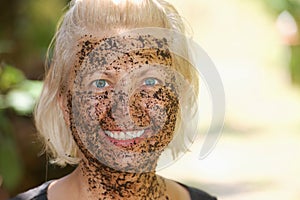 Portrait of happy woman with a coffee pilling mask