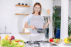 portrait happy woman cooking healthy food vegetable salad in kitchen with online tablet