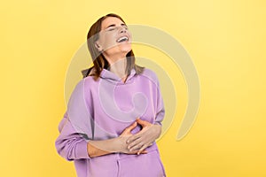 Happy woman with dark hair holding belly, laughing, hearing funny joke or anecdote. photo