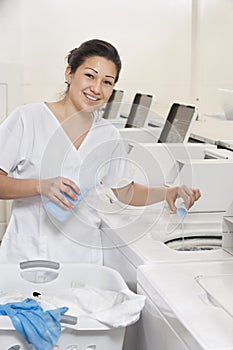 Portrait of a happy woman employee pouring detergent in washer