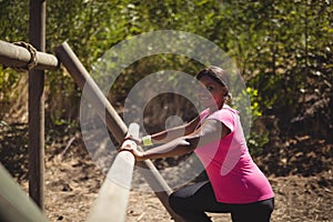 Portrait of happy woman exercising on outdoor equipment during obstacle course