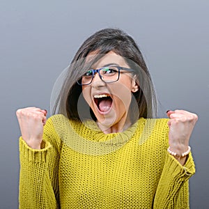 Portrait of happy woman exults pumping fists ecstatic celebrates success against gray background photo