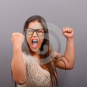 Portrait of happy woman exults pumping fists ecstatic celebrates success against gray background photo