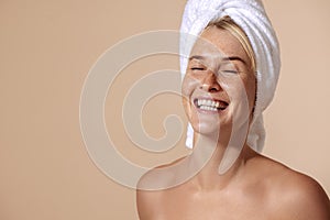 Portrait of a happy woman with freckles wrapped her hair with a white towel