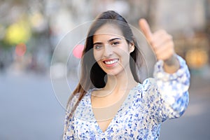 Portrait of a happy woman gesturing thumbs up in the street