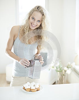 Portrait of happy woman grating chocolate on cupcakes at counter photo