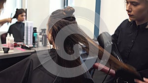 Portrait of happy woman at the hair salon. Professional hair styling concept. Hairdresser drying girl long hair using