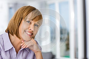 Portrait of happy woman with hand on chin at home