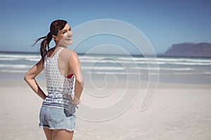 Portrait of happy woman with hands on hip standing at beach