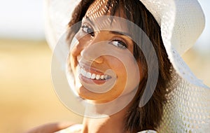 Portrait, happy woman in hat at field or countryside in summer outdoor, beauty or health. Face, smile and young person