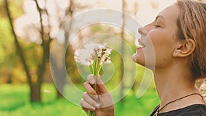 Portrait happy woman holding bouquet ripe dandelions in hands, smiling face enjoys nature. girl blows on dandelions