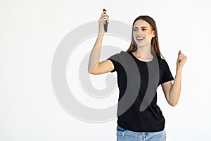 Portrait of a happy woman holding mobile phone and celebrating a win isolated over white background