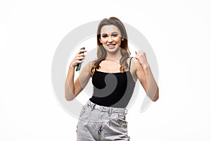 Portrait of a happy woman holding phone and celebrating a win isolated over white background