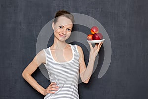 Portrait of happy woman holding saucer with ripe red nectarines