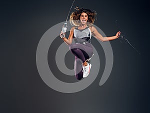 Portrait of happy woman jumping with bottle of water