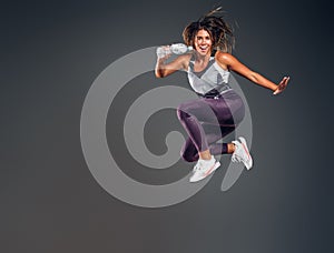 Portrait of happy woman jumping with bottle of water