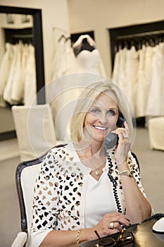 Portrait of a happy woman listening to telephone receiver in bridal store