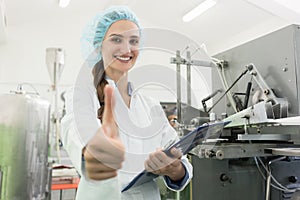 Portrait of happy woman manufacturing specialist showing thumbs up