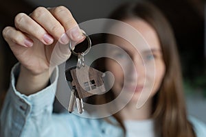 Portrait of happy woman moving in showing keys to new apartment. Cute woman standing in her new house showing the keys