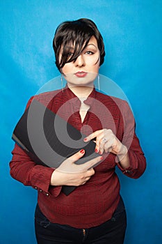 Portrait of happy woman in office, standing with folder on bluw studio background