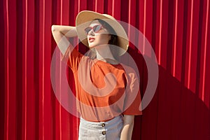 Portrait of a happy woman opposite her red wall. Natural smile. Sunny day.
