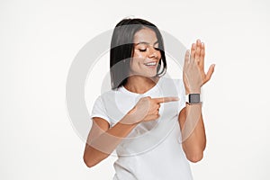 Portrait of a happy woman pointing finger at smart watch