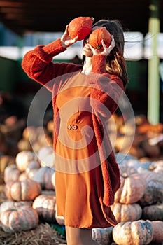 Portrait of happy woman with ripe orange pumpkins in hands close eyes near wagon with orange pumpkin on farmers market