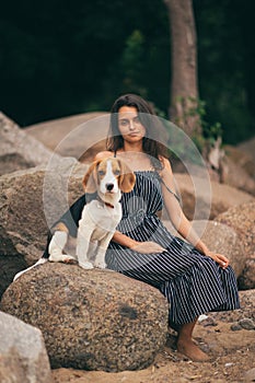 Image of happy woman 20s hugging her dog while walking along the beach