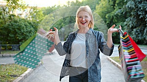 Portrait of happy woman shopaholic spinning outdoors with shopping bags smiling