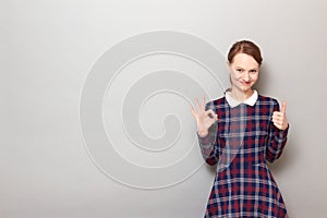 Portrait of happy woman showing okay gesture, giving thumb up sign