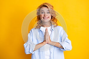 Portrait of happy woman smiling and saying prayer. Pretty girl enjoys peaceful atmosphere, holds hands in praying