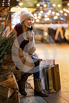 Portrait of happy woman spending time with christmas shopping outdoors in city.