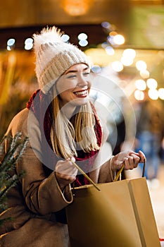 Portrait of happy woman spending time with christmas shopping outdoors in city.