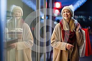 Portrait of happy woman spending time with christmas shopping outdoors in city.