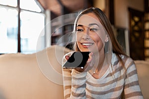 Portrait of happy woman using voice assistant on cellphone
