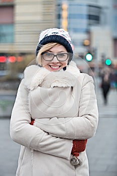 Portrait of happy woman in warm clothing standing arms crossed on city street