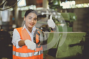 Portrait happy woman worker working in heavy industry metal factory Asian smiling thumbs up