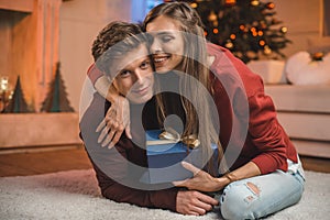 portrait of happy woman with wrapped gift hugging boyfriend