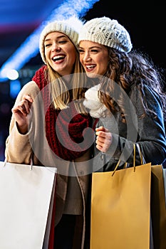 Portrait of happy women enjoying christmas shopping together in the city