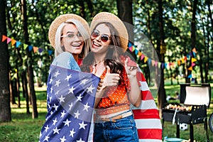 portrait of happy women in hats and sunglasses with american flag