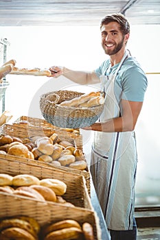 Portrait of happy worker holding basket of bread