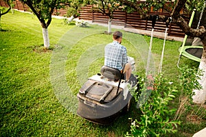 Portrait of happy worker using lawn tractor for grass cutting