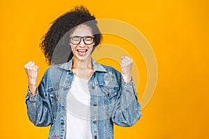 Portrait of a happy young african american black woman celebrating success isolated over yellow background