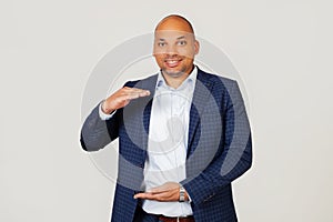 Portrait of happy young african american businessman guy gesturing with hands showing big and large size sign, symbol of measure.