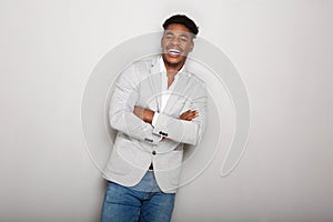 Happy young african american businessman laughing with arms crossed against gray background