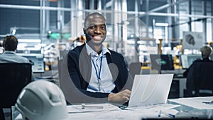 Portrait of a Happy Young African American Engineer Working on Laptop Computer in an Office at Car