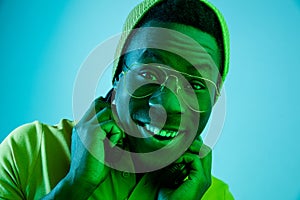 Portrait of a happy young african american man smiling on black neon background