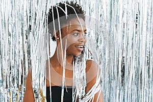 Portrait of happy young African American woman in black top on sparkly silver background